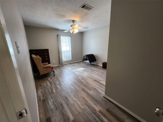 unfurnished room featuring hardwood / wood-style flooring, ceiling fan, and a textured ceiling