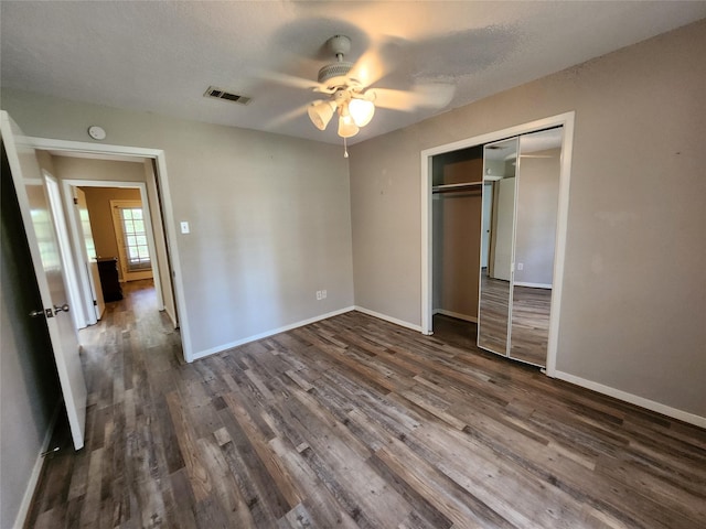 unfurnished bedroom featuring ceiling fan, dark hardwood / wood-style flooring, a textured ceiling, and a closet