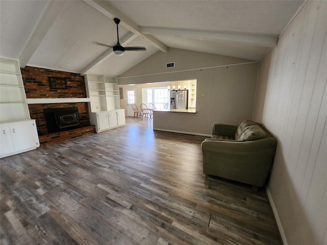 living room featuring a wood stove, ceiling fan with notable chandelier, wooden walls, hardwood / wood-style flooring, and vaulted ceiling with beams