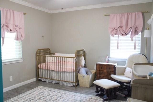 bedroom featuring crown molding, hardwood / wood-style flooring, and a crib