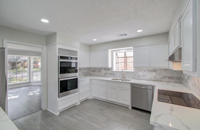 kitchen with sink, light hardwood / wood-style flooring, appliances with stainless steel finishes, light stone counters, and white cabinetry