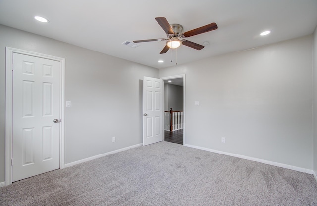 empty room with dark colored carpet and ceiling fan