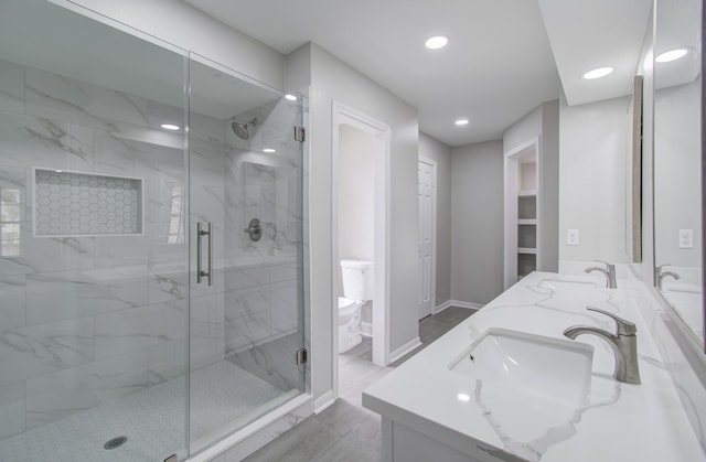 bathroom featuring vanity, toilet, and a shower with shower door