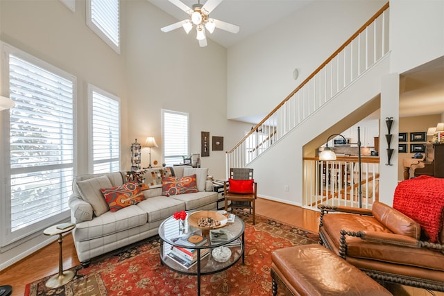 living room with a high ceiling, hardwood / wood-style flooring, and ceiling fan