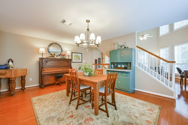 dining area with ceiling fan with notable chandelier and light wood-type flooring