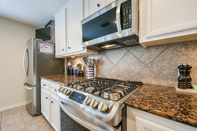 kitchen featuring white cabinets, backsplash, stainless steel appliances, and dark stone counters