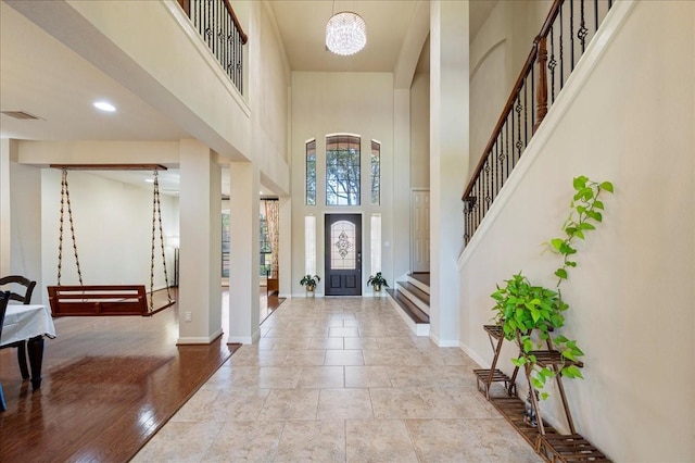 entryway with a towering ceiling, light hardwood / wood-style floors, and an inviting chandelier