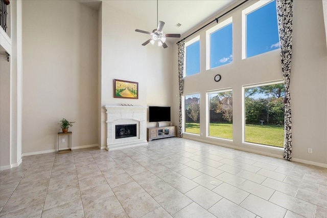 unfurnished living room with ceiling fan, a towering ceiling, and light tile patterned flooring