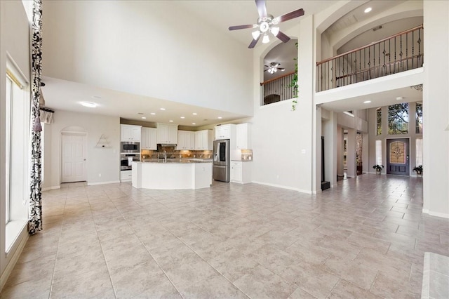 unfurnished living room with a high ceiling and ceiling fan