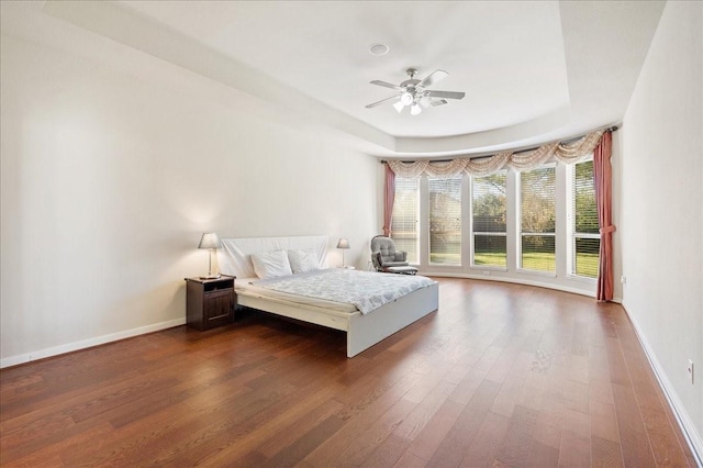 unfurnished bedroom with a raised ceiling, ceiling fan, and dark wood-type flooring