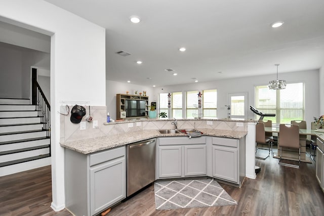 kitchen with dishwasher, decorative light fixtures, light stone counters, and dark wood-type flooring