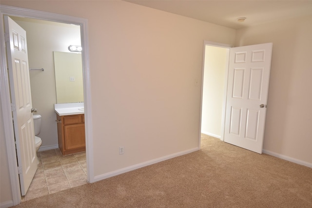 unfurnished bedroom with light carpet and ensuite bath