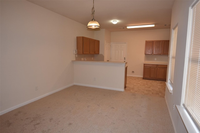 kitchen with kitchen peninsula, light colored carpet, and decorative light fixtures