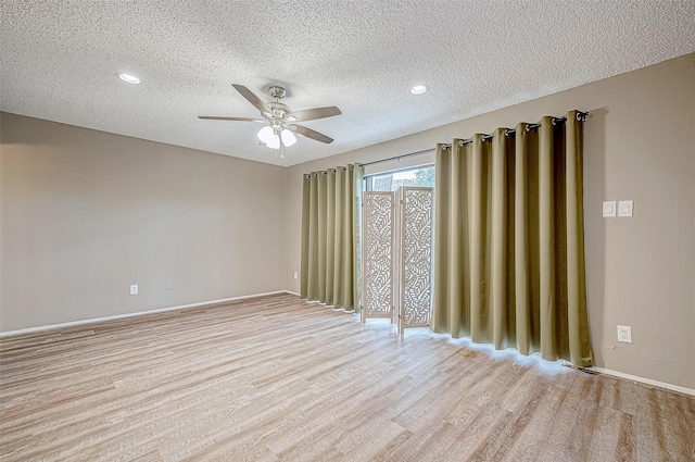 empty room with ceiling fan, light hardwood / wood-style flooring, and a textured ceiling