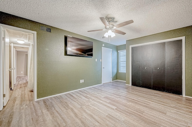 unfurnished bedroom featuring a closet, ceiling fan, light hardwood / wood-style flooring, and a textured ceiling