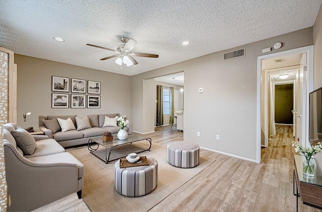 living room featuring a textured ceiling, light hardwood / wood-style flooring, and ceiling fan