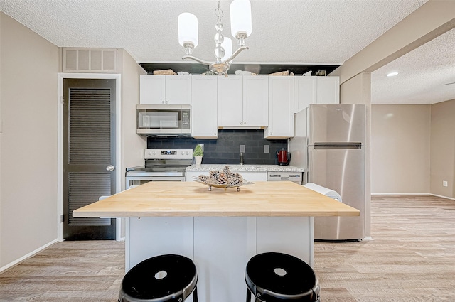 kitchen featuring decorative light fixtures, light hardwood / wood-style floors, a kitchen island, and stainless steel appliances