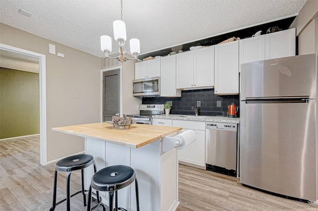 kitchen with a center island, white cabinets, stainless steel appliances, and light hardwood / wood-style flooring