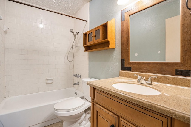 full bathroom with a textured ceiling, vanity, toilet, and tiled shower / bath combo