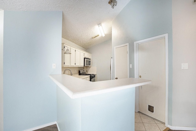 kitchen with white cabinetry, stainless steel appliances, kitchen peninsula, vaulted ceiling, and a textured ceiling