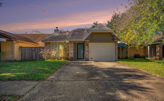 ranch-style home with a garage and a yard