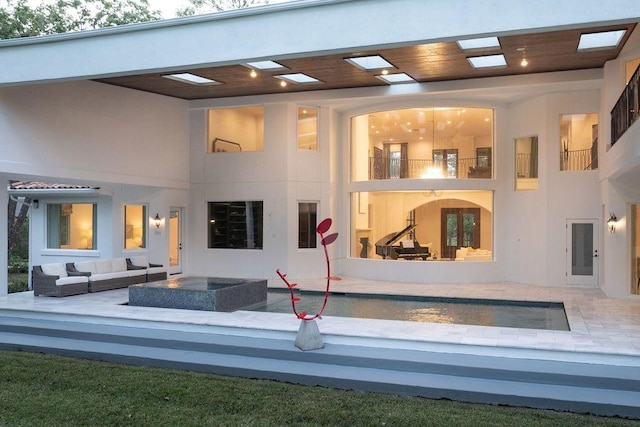 rear view of property with outdoor lounge area, a jacuzzi, and a balcony