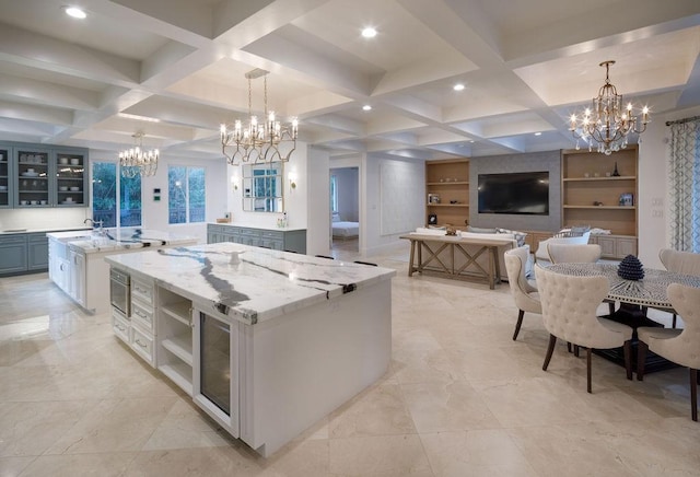 kitchen with a large island, light stone countertops, hanging light fixtures, and coffered ceiling