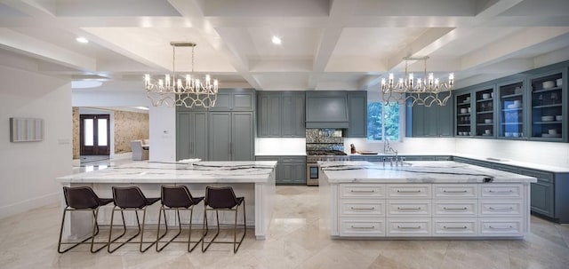 kitchen featuring a large island, light stone counters, coffered ceiling, and custom exhaust hood