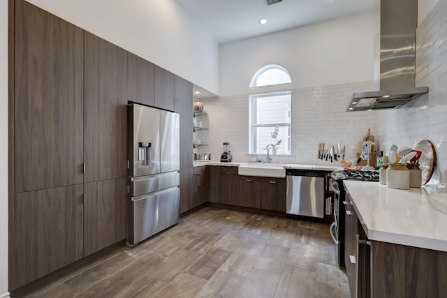 kitchen featuring sink, wall chimney exhaust hood, dark hardwood / wood-style floors, backsplash, and appliances with stainless steel finishes