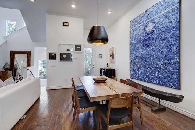 dining room featuring crown molding, dark wood-type flooring, and a high ceiling