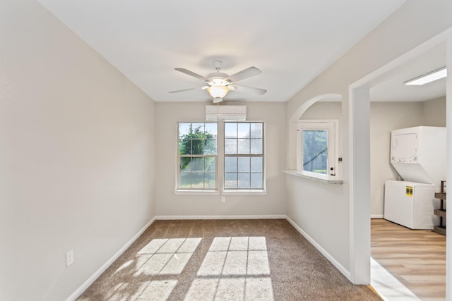 unfurnished room featuring light wood-type flooring, ceiling fan, and stacked washer and clothes dryer