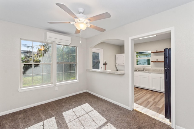 carpeted spare room with ceiling fan, sink, and a wall unit AC