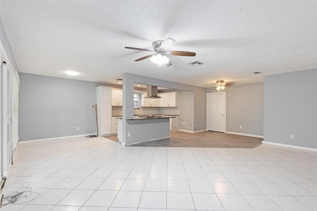 unfurnished living room with ceiling fan, light tile patterned floors, and a textured ceiling