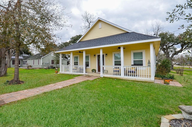 farmhouse-style home with ceiling fan, covered porch, and a front yard