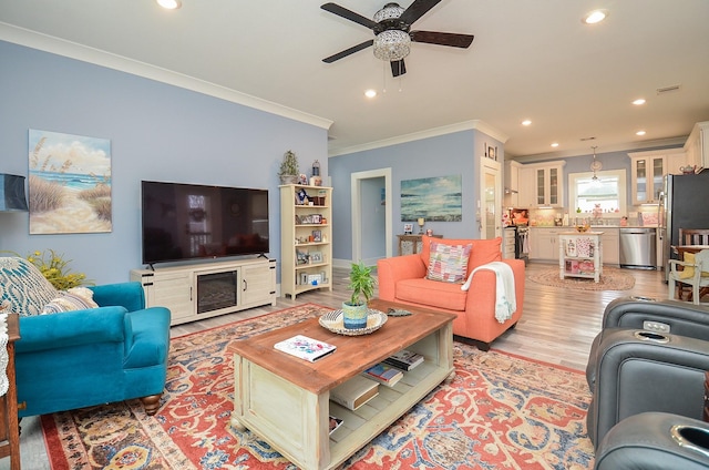 living room with crown molding, light hardwood / wood-style flooring, and ceiling fan