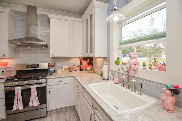 kitchen with white cabinetry, wall chimney exhaust hood, and stainless steel gas range