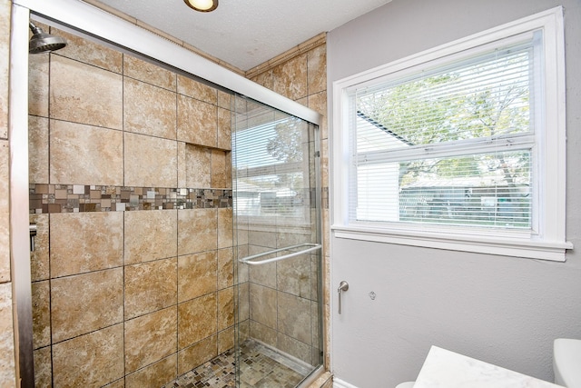 bathroom featuring a textured ceiling and a shower with door