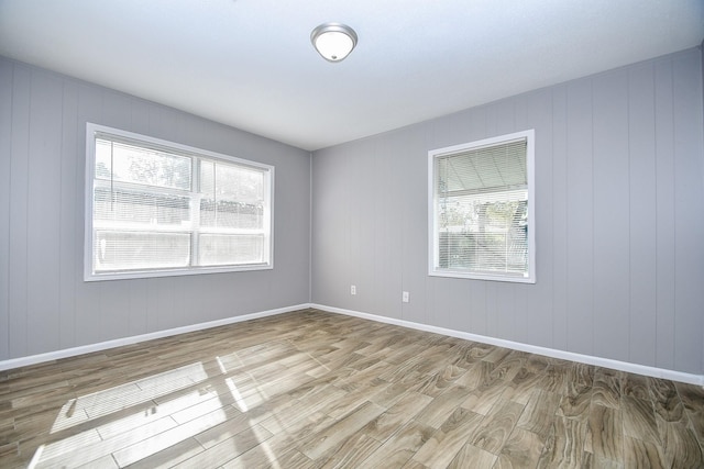 empty room with hardwood / wood-style floors and wooden walls