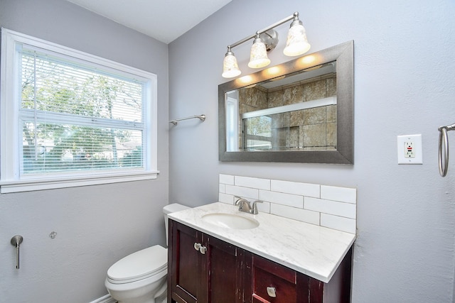 bathroom featuring a shower with door, vanity, and toilet