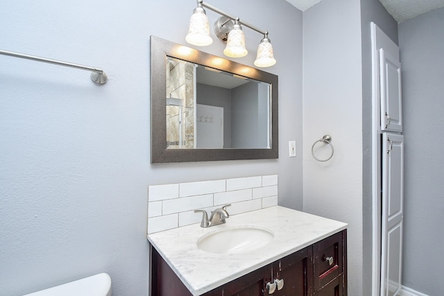 bathroom featuring vanity, toilet, and decorative backsplash