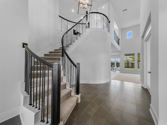 tiled entryway featuring a high ceiling and a chandelier