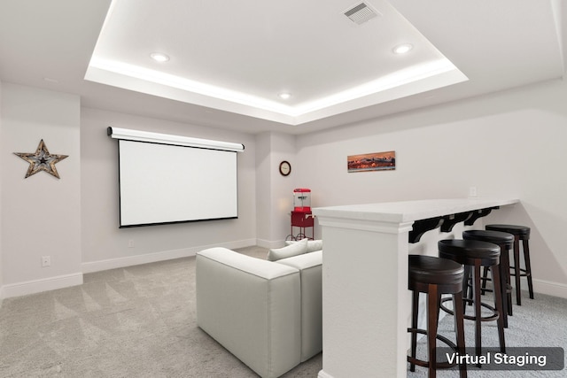 home theater with a raised ceiling and light carpet