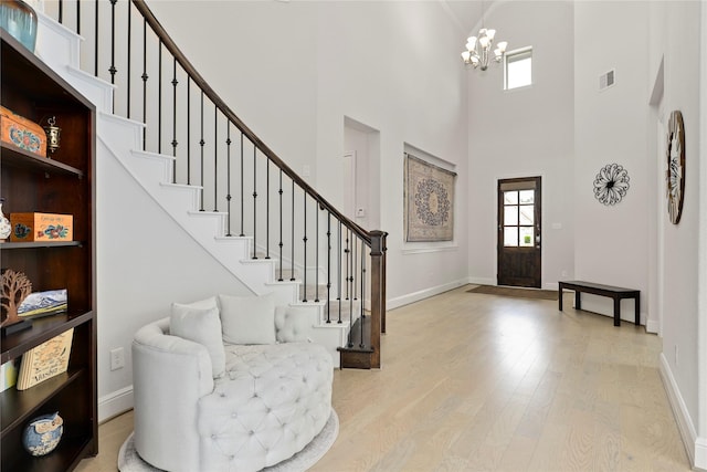 foyer entrance with light hardwood / wood-style floors, a high ceiling, and an inviting chandelier