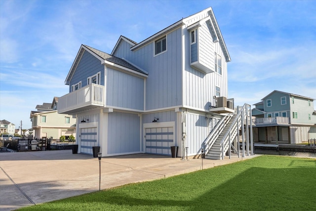 rear view of property featuring a balcony, a garage, cooling unit, and a lawn