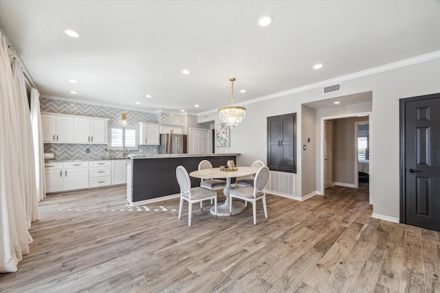 dining room featuring light wood-type flooring and ornamental molding