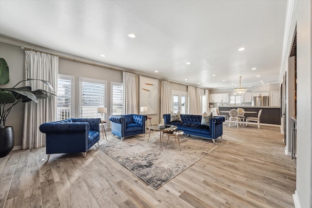 living room with a textured ceiling, light wood-type flooring, and crown molding