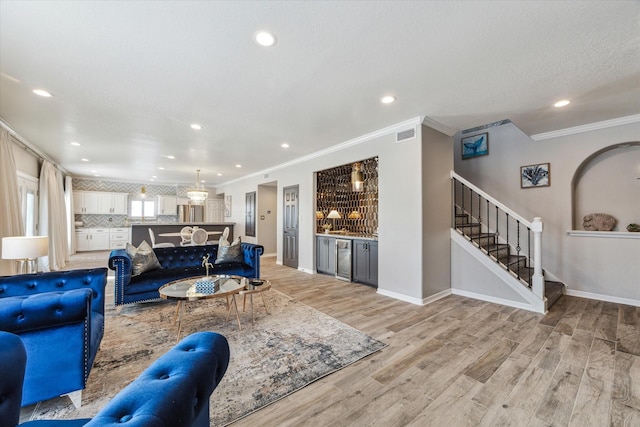 living room featuring light wood-type flooring, crown molding, and beverage cooler