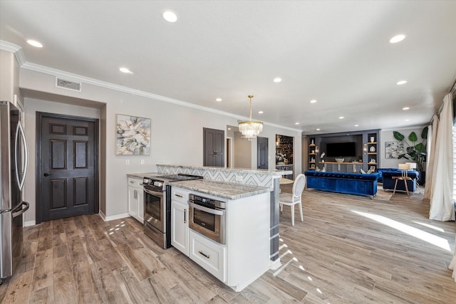 kitchen with white cabinetry, stainless steel appliances, pendant lighting, light wood-type flooring, and ornamental molding