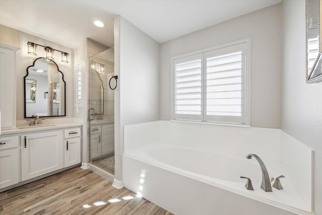 bathroom featuring wood-type flooring, vanity, and shower with separate bathtub