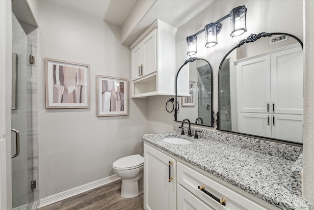 bathroom with wood-type flooring, vanity, toilet, and walk in shower